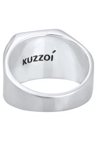 Sidabrinis žiedas su plokščiu viršumi ir lygiu, poliruotu paviršiumi. Turi šešiakampį formą ir viduje išgraviruota "KUZZOI".
