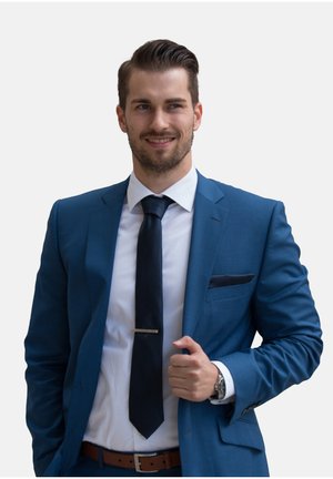 Costume bleu sur mesure avec une pochette, chemise blanche et cravate foncée. Comprend une pince à cravate argentée et une ceinture en cuir marron ; montre au poignet.