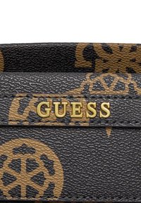 Portafoglio in materiale testurizzato nero con logo dorato "GUESS" e accenti marroni con motivi decorativi a cerchio.
