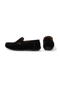 Sorte ruskinds slip-on sko med hvid syning, afrundet tå og struktureret gummisål. Bagfra ses en kort, blød krave.