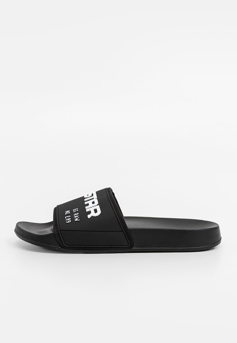 Czarne klapki z szerokim paskiem, na którym znajduje się biały napis "G-STAR RAW NR E89" na białym tle.