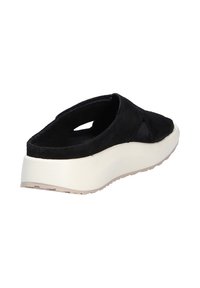 Scarpa nera in suede, slip-on con suola a cuneo, dotata di dettagliintagliati sui lati e una base bianca a contrasto. Suola in gomma texturizzata.
