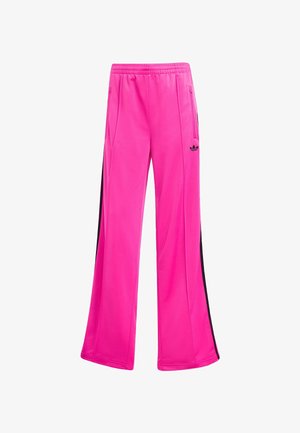 Pantalones deportivos de poliéster rosas con un diseño de pierna ancha, que cuentan con franjas laterales negras y un logo de Adidas en la pierna izquierda.