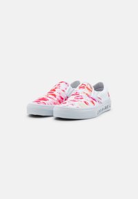 Chaussures à enfiler en toile avec une base blanche ornée d'un motif abstrait multicolore en rose, rouge et orange. Semelle en caoutchouc blanche avec détail de texte.