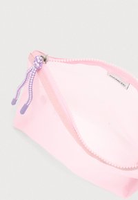 Ροζ διάφανη καλλυντική θήκη με κλείσιμο φερμουάρ, που διαθέτει μοβ και λευκό πλεκτό τράβηγμα. Λεία υφή και μινιμαλιστικός σχεδιασμός.