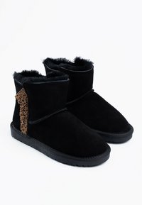 Botas ankle de ante negro con un forro suave, que presentan un acento de estampado de leopardo en el lateral y una suela de goma negra texturizada.