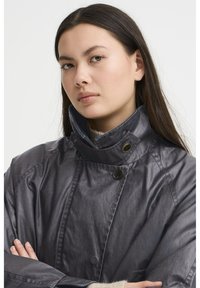 Grau, leichte Jacke mit hohem Kragen, ausgestattet mit Knopfdetails und einer glatten, leicht glänzenden Textur.