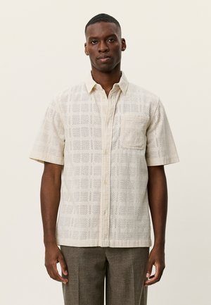 Kortærmet skjorte med knapper i lys beige med ternet mønster, med en påsyet lomme, lavet af tekstureret stof.