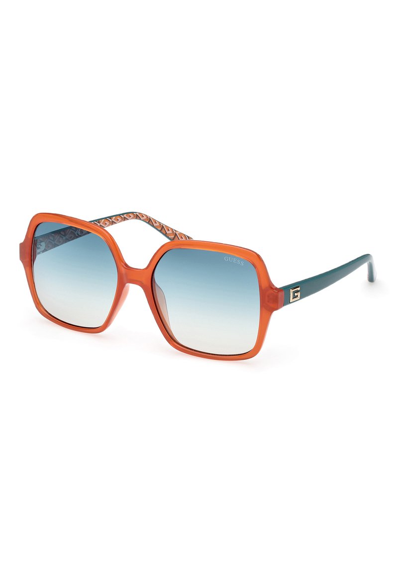 Neliönmuotoiset aurinkolasit oranssisilla läpinäkyvillä kehyksillä, sinisillä gradienttilinsseillä ja sinivalkoraidallisilla varsilla. Mukana on logotieto temppeleissä.