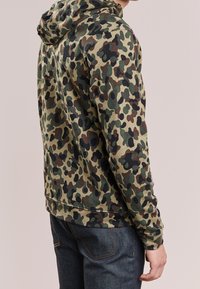 Felpa con cappuccio con stampa mimetica in verde, marrone e nero. Tessuto morbido con maniche lunghe e cappuccio, progettata per una vestibilità casual.