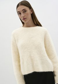Pluizig crèmekleurig sweater met een ronde hals, lange mouwen en een ontspannen pasvorm, met een zachte textuur en een rechte zoom.