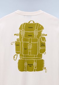 Γραφικό πράσινου σακιδίου πλάτης σε ύφασμα κρεμ, με επισημασμένα τμήματα για αντικείμενα: κάμερα, ρούχα, νερό, φαγητό, χάρτης και υπνόσακος.