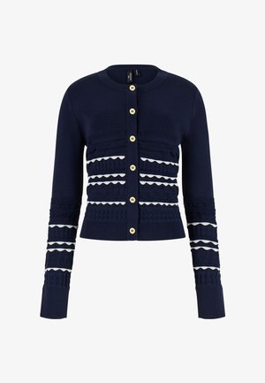 Cardigan blu navy con bottoni beige, motivi a maglia strutturata e strisce bianche a zigzag sul petto e sulle maniche.