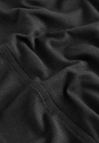 Schwarzer Stoff mit einer sanften Textur, der Falten und Nähte zeigt. Das Material scheint leicht und mit einer glatten Oberfläche versehen zu sein.