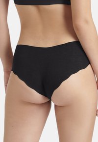 Schwarze Shorts aus weichem, dehnbarem Material. Mit einem gewellten Saumdesign und einer mittelhohen Form für Komfort und Bedeckung.