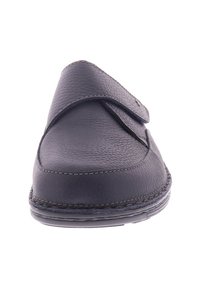 Zwarte leren instappers met een textuur op het oppervlak en een verstelbare band over de bovenkant, zichtbare stiksels langs de randen van de zool.