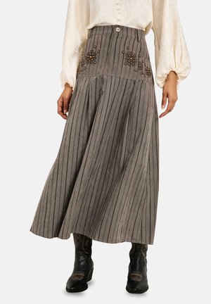 Falda gris de rayas de talle alto con bordado floral, combinada con blusa crema y botas negras bordadas, mostrada desde la mitad del torso hasta los pies.