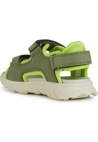 Zelené sandály s texturovaným svrškem, které mají jasně limetkově zelenou podšívku. Otevřený design, nastavitelné popruhy a lehká smetanová podrážka.