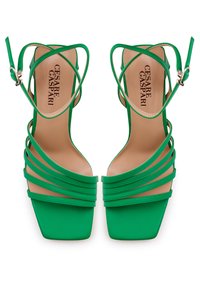 Sandalias de tacón alto verdes con punta cuadrada, que cuentan con múltiples correas delgadas y una plantilla acolchada. Nombre de la marca visible en la plantilla.