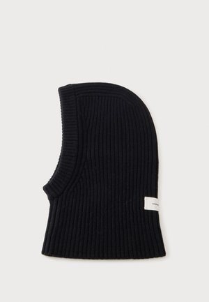 Cagoule en maille côtelée noire avec une large ouverture au niveau du cou et une petite étiquette blanche rectangulaire sur le côté.