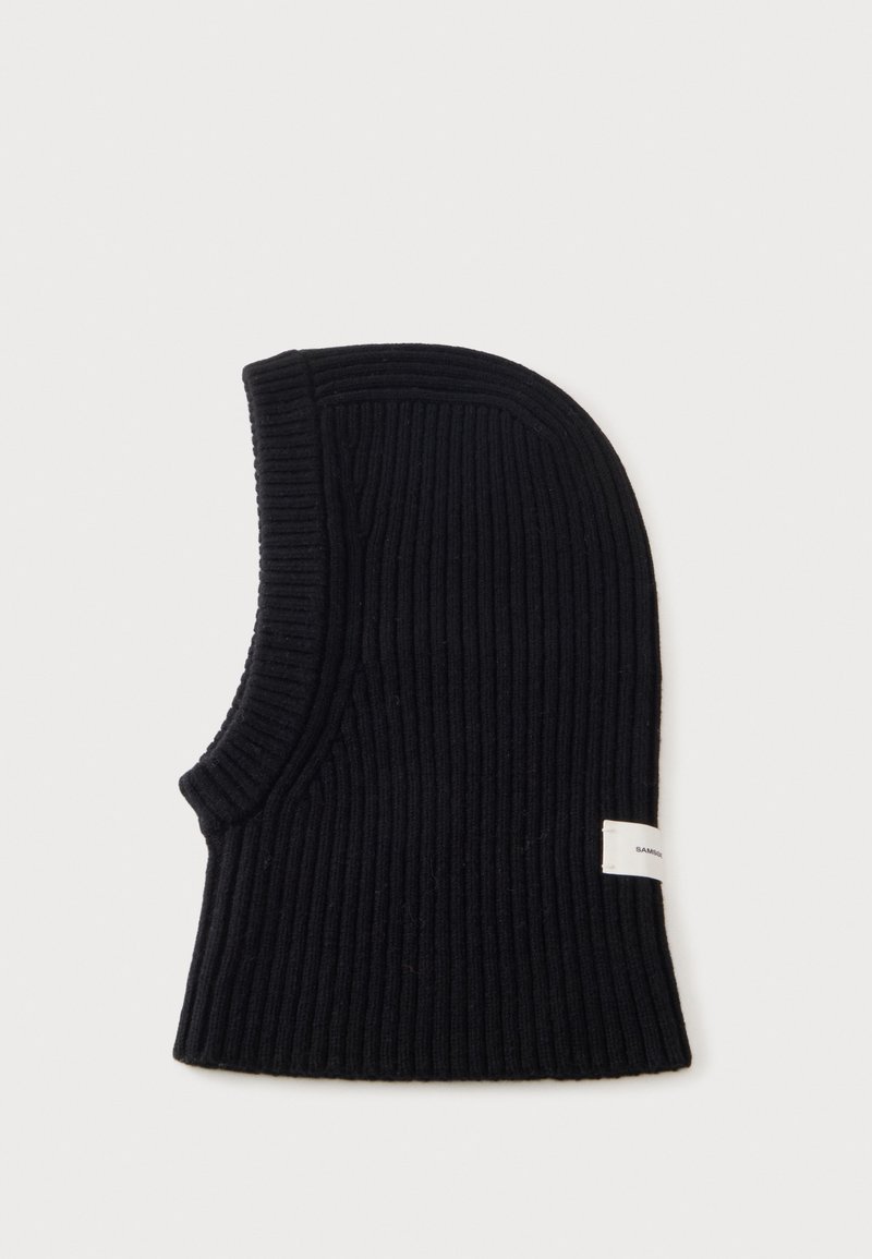 Cagoule en maille côtelée noire avec une large ouverture au niveau du cou et une petite étiquette blanche rectangulaire sur le côté.