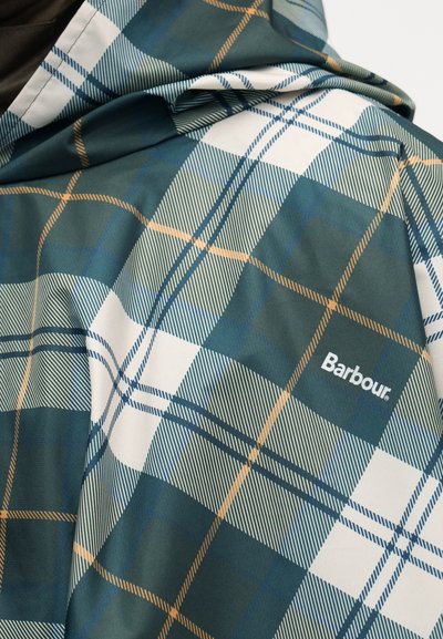 Tissu à motif écossais vert, blanc et orange avec le logo Barbour brodé sur une veste pliée.