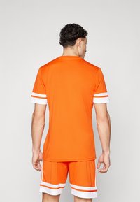 Orange athletic jersey with short sleeves; white stripes on sleeves. Lightweight fabric, regular fit. Worn with matching orange shorts.
