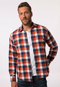 Camisa de franela en un patrón de cuadros rojo, blanco y azul marino, con mangas largas, cierre de botones en el frente y dos bolsillos en el pecho.