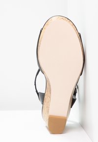 Sandale noire à semelle en liège, doté d'une semelle inférieure lisse de couleur claire et d'accents texturés sur la partie supérieure. Le design permet la ventilation du pied.
