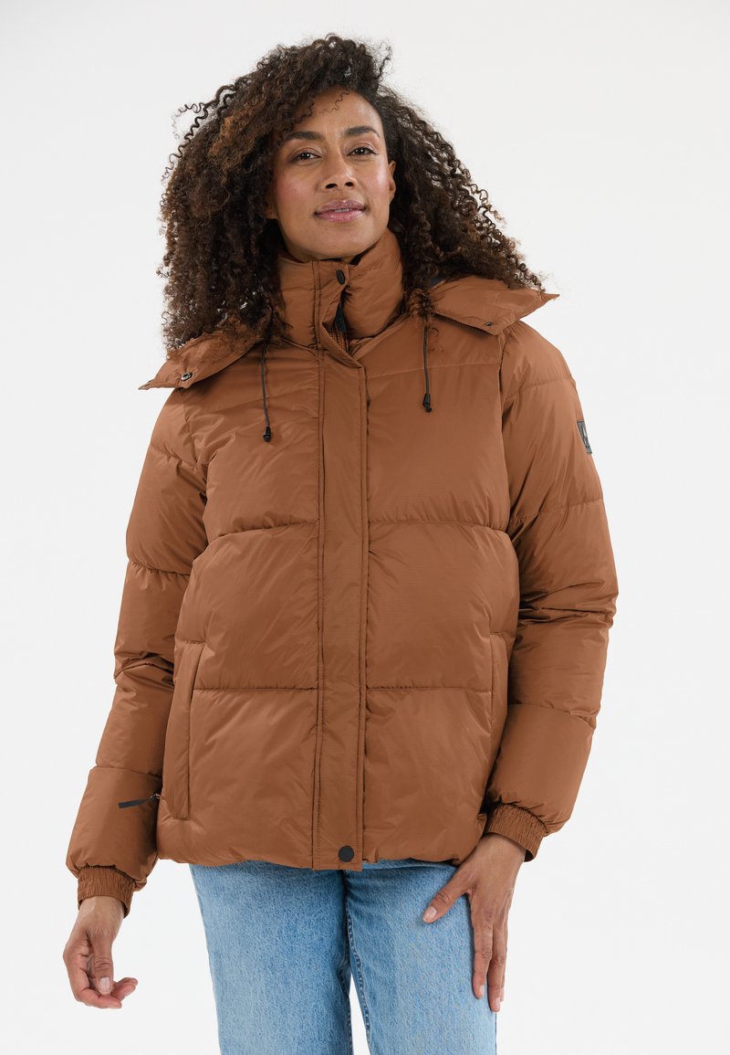 Brun pufferjakke med højt krave, vandret syninger, justerbare snore og elastiske manchetter. Båret over blå jeans.