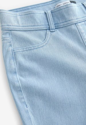 Legging en denim bleu clair avec un design ajusté, des coutures visibles, une seule poche avant et une texture lisse.