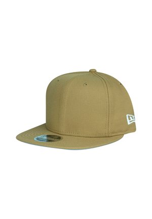 Casquette snapback beige à visière plate avec six œillets de ventilation et un petit logo brodé blanc sur le côté.