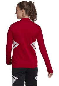 Rode longsleeve top met een hoge kraag, voorzien van witte accentpanelen en een gestructureerd ontwerp op de achterkant. Glad materiaal met een atletische pasvorm.