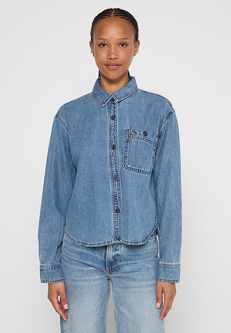 Denim shirt met een button-down kraag, borstzak en zwarte knopen. Lichtblauwe kleur met vervaagde textuur, cropped ontwerp en gestikte accenten.