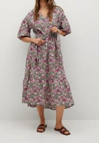 Robe midi florale à manches courtes, dotée d'une ceinture et d'un ourlet à volants. Les couleurs incluent des motifs floraux roses, verts et blancs sur un fond gris.