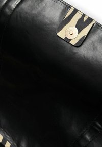 Intérieur en cuir noir d'un sac avec un rabat texturé à motif animalier marron et noir et une fermeture à bouton-pression métallique.