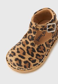 Παιδικό παπούτσι Mary Jane από καστόρι με λεοπάρ σχέδιο, κυματιστές άκρες και λουράκι με ασημί αγκράφα σε λευκό φόντο.
