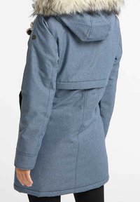 Giacca outdoor blu con cappuccio e bordo in pelliccia sintetica, caratterizzata da un tessuto testurizzato, maniche lunghe e un design di lunghezza media.
