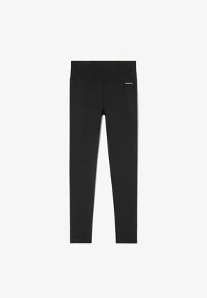 Leggings negros con canalé y una cinturilla alta. Fabricados con un tejido elástico de textura suave. Un branding mínimo aparece en la cinturilla.