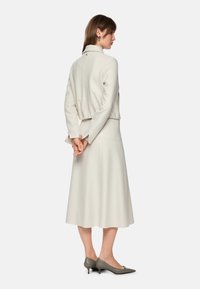 Cream-colored, textured sweater and skirt set. Sweater has a slightly cropped design with a collar; skirt is ankle-length and fitted.