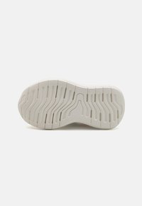 Shoe outsole made of rubber, featuring a textured white pattern with wavy grooves and ridges for traction and grip.