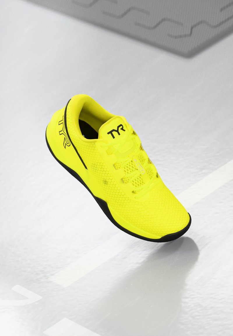 Bright yellow athletic shoe with mesh upper, black outsole, and TYR logo on the side. Features a lightweight design and lace closure.
