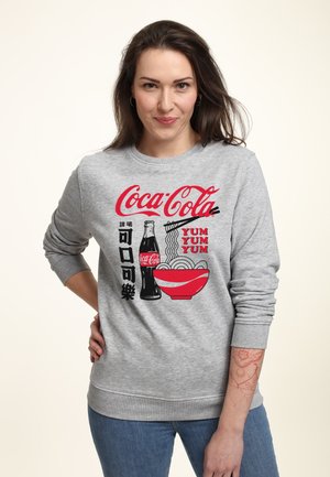 Felpa grigia con il logo della Coca-Cola in rosso, accompagnata da una grafica di una bottiglia di soda e una ciotola di noodle. Maniche e orlo a costine.