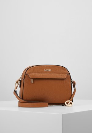 Sac bandoulière en cuir marron texturé avec poche avant zippée, matériel doré et une fine sangle réglable sur une surface blanche.