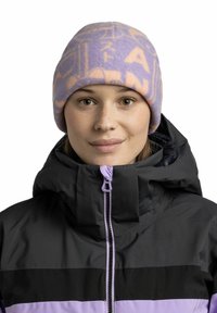 Purple fleece beanie with a soft texture and light orange graphic print. Worn with a black and purple zippered jacket featuring a high collar.