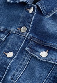 Tummansininen farkkutakki hopeisilla neppareilla, päällitikkauksilla ja kahdella etutaskulla. Takissa on klassinen kaulus ja jämäkkä muotoilu.