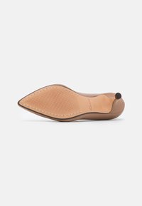 Escarpin à talon haut en cuir fauve à bout pointu, montrant une semelle texturée et un talon stiletto fin sur fond blanc.