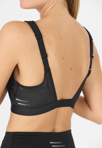 Svart sportbh med justerbara axelremmar, ett mesht bakstycke och horisontella ränder på bandet för extra designdetaljer.