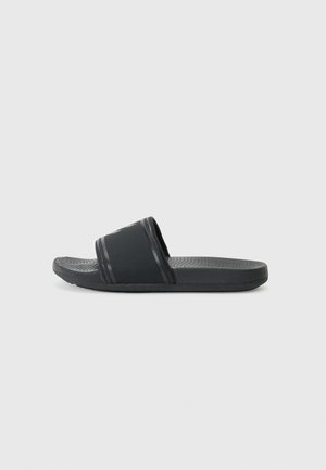 Schwarze Rutsch-Sandalen mit einer strukturierten Sohle, breitem Oberriemen und subtilen horizontalen Streifen entlang der Kanten. Hergestellt aus weichem, strapazierfähigem Material.