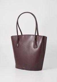 Mauve leren schoudertas met een zachte textuur, verlengde handvatten en een minimalistisch ontwerp. Kenmerkt zich door subtiele branding aan de basis.